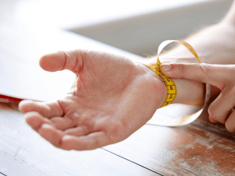 person measuring their wrist with a tape measure