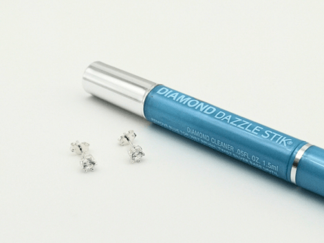 diamond dazzle stik beside a pair of diamond stud earrings