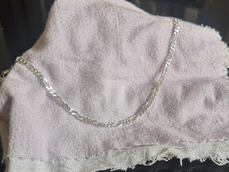 Silver figaro chain on a purple napkin