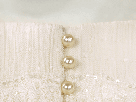An ivory wedding dress with peach pearl buttons