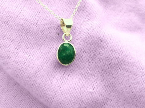 Oval emerald pendant on a purple napkin