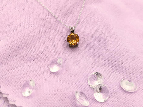 round citrine necklace on a purple napkin with colourless gems in the foreground