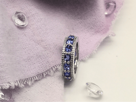 Silver tanzanite eternity ring on a purple napkin