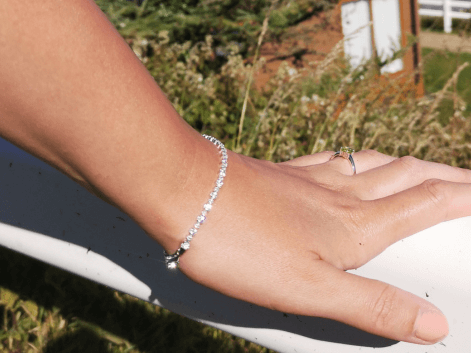 Woman wearing a tennis bracelet leaning on a white fence