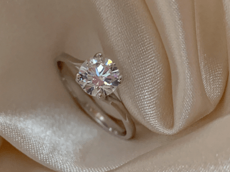 A gold diamond solitaire ring on a white silk napkin