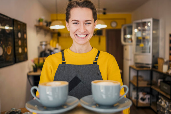 Dueña de cafetería entrega dos tazas de Café Aromas a sus clientes