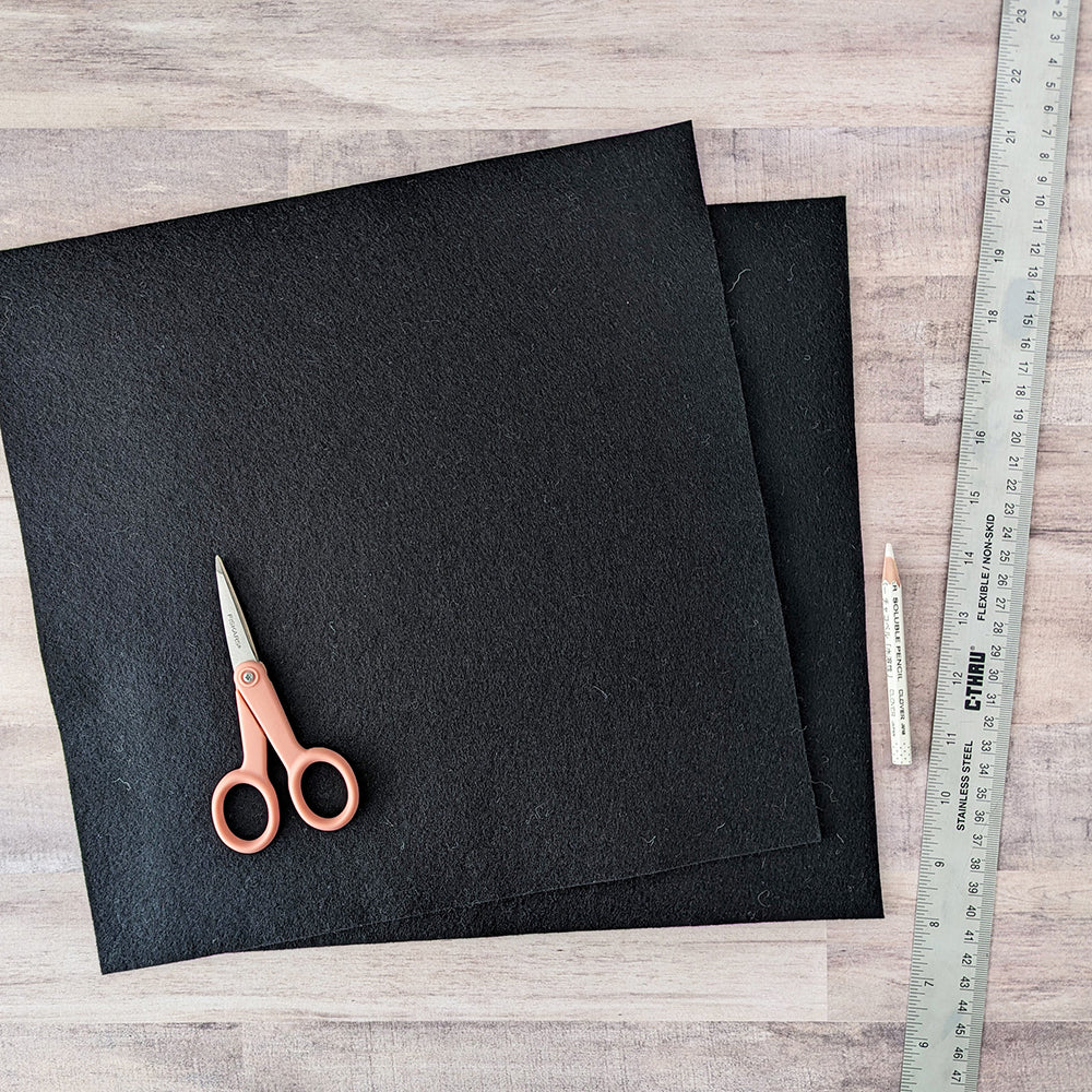 Cutting black felt into squares for pillow