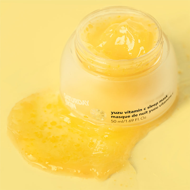 A jar of Saturday Skin Yuzu Vitamin C Sleep Mask with some of the mask spread out to show the viscous and lemony quality of the product.