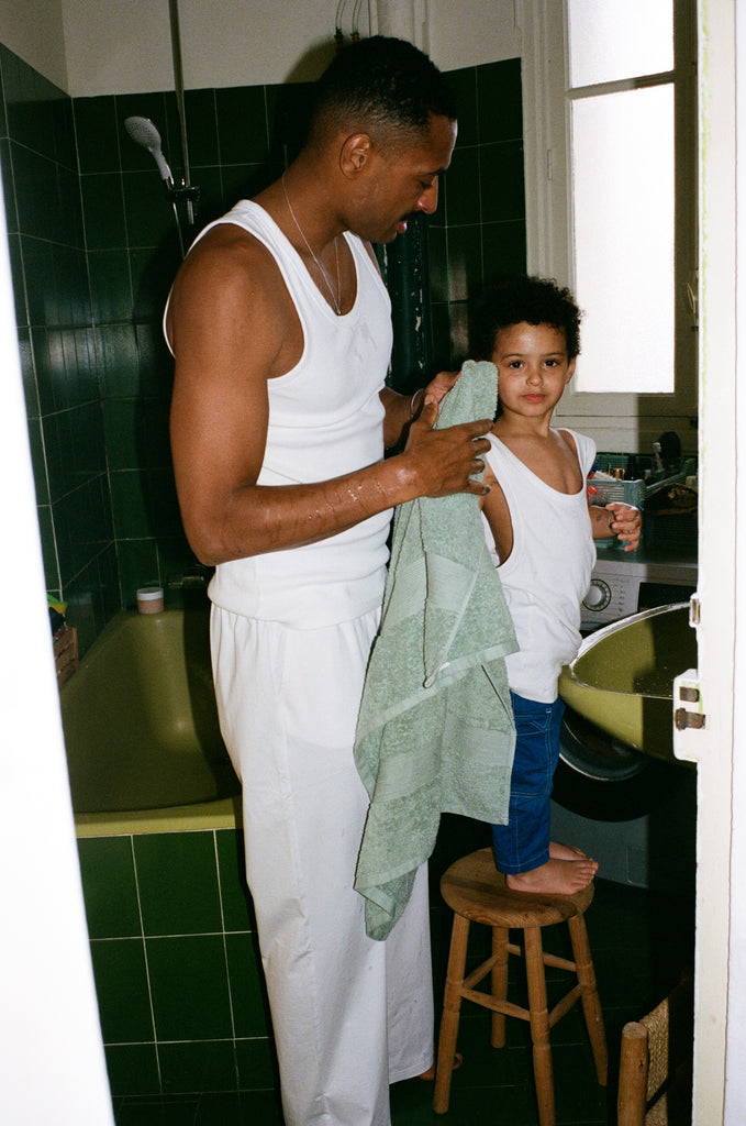 Portrait of Georges and Eli in the bathroom, they are both wearing OMEAR basics