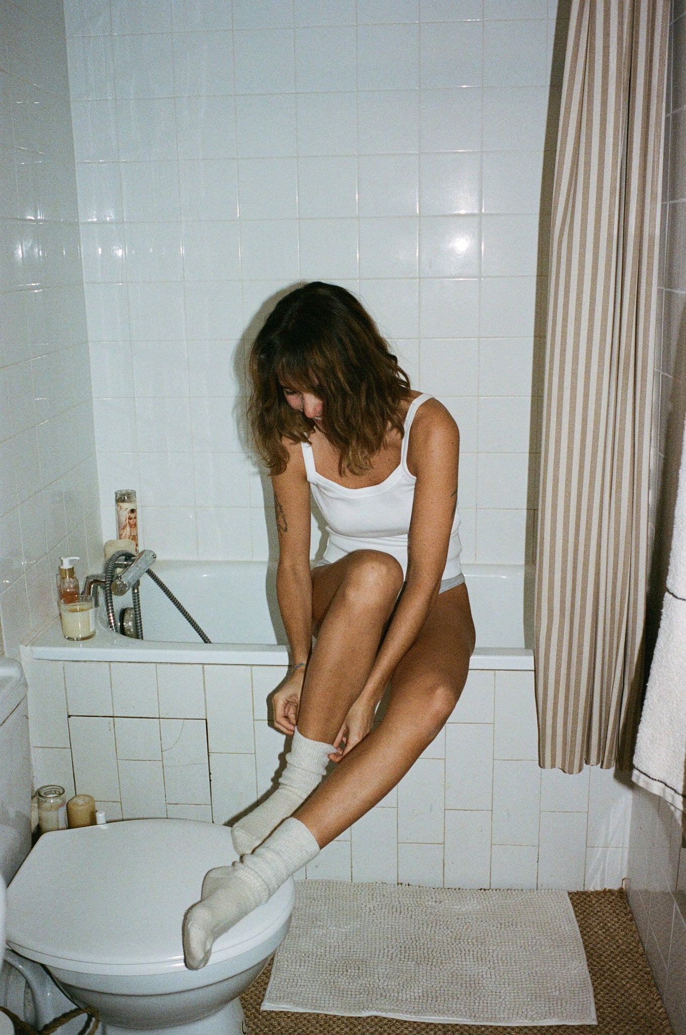 Portrait de Marine Neuilly dans sa salle de bain portant le débardeur à fines bretelles blanc OMEAR