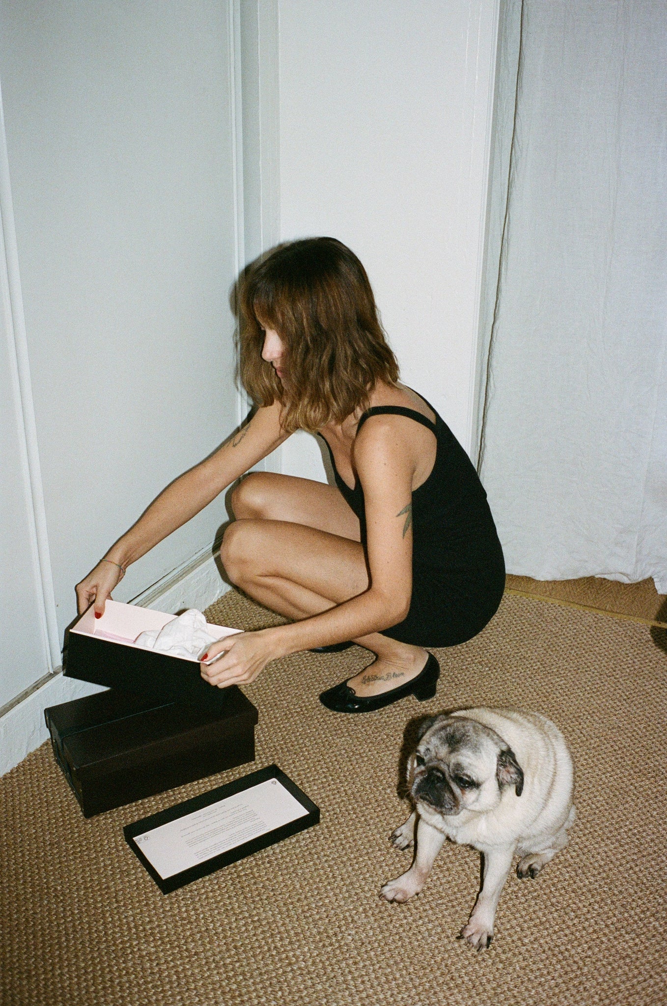 Portrait de Marine Neuilly dans son appartement portant la robe à fines bretelles noire OMEAR