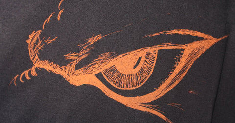 ElRat's Kaiju Eye Tee: Striking black shirt with a hand-drawn kaiju eye in vibrant orange print. Edgy, unique, and eye-catching fashion statement