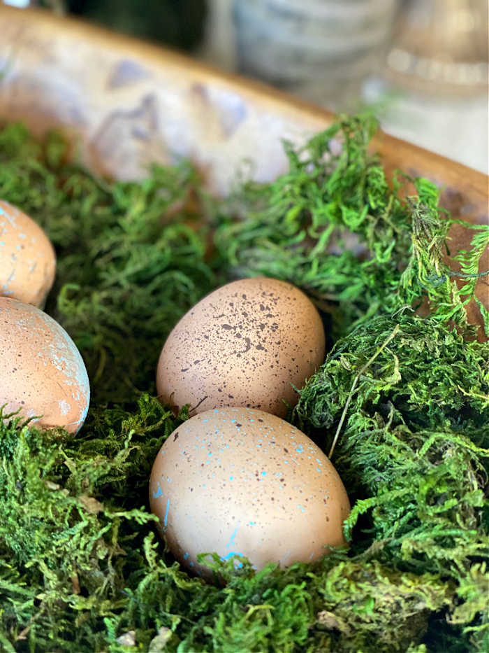 Splatter painted blown eggs in a bowl with moss