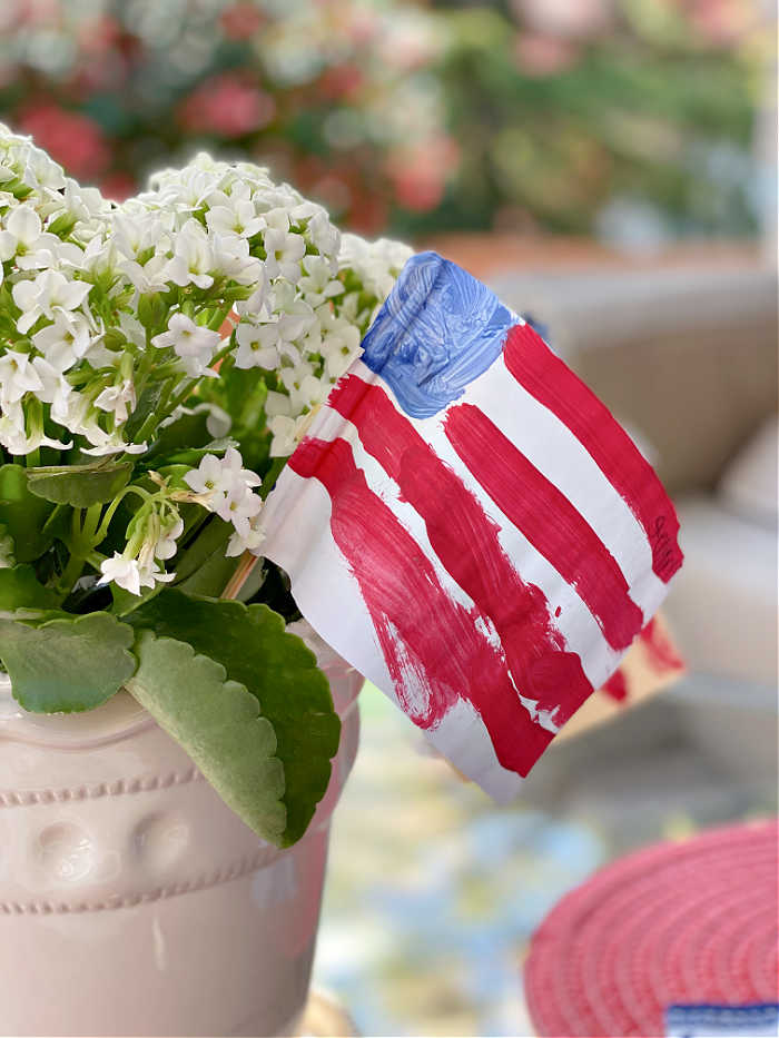 Photo of paper painted American flag in a flower pot on a glass table
