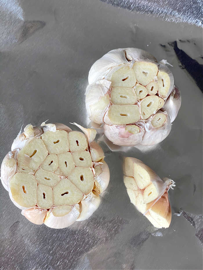 How to roast a garlic bulb in the oven recipe. This easy method delivers creamy and fragrant garlic every time! Serve roasted garlic on its own with crusty bread of mix into any number of delicious recipes. #garlic #roastedgarlic #secretsauce