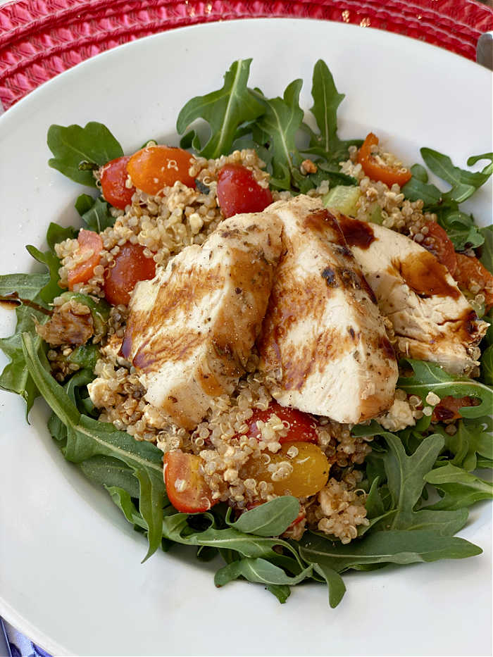 Sliced chicken breast on a bed of quinoa and arugula salad