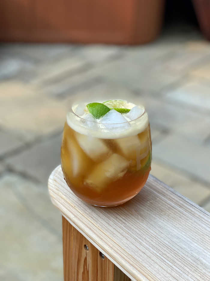 Photo of dark and stormy cocktail on an Adirondack chair arm