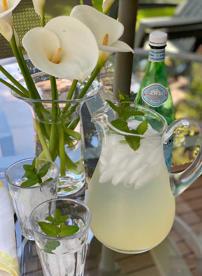 photo of lemonade in a pitcher with calla lilies in a vase and ice in glasses with mint garnish