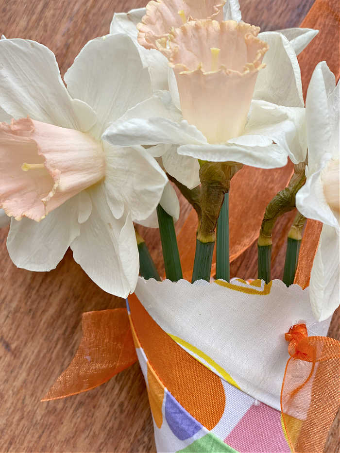 Close up photo of flowers hanging in a paper and fabric cone