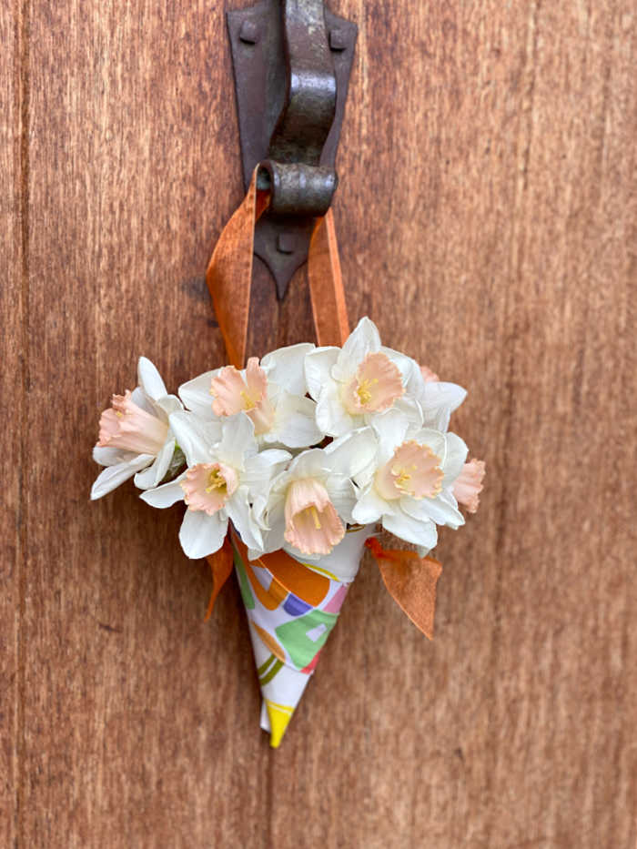 Flowers in a fabric cone hanging from a front door knocker of house