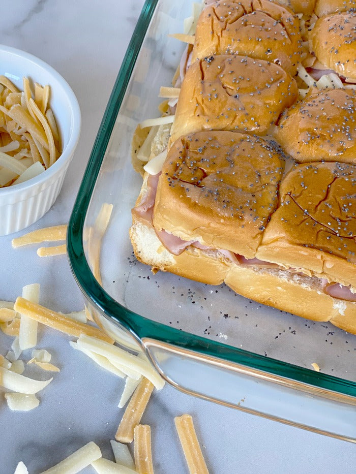 Ham and cheese sliders on Hawaiian rolls with honey mustard dipping sauce. This easy recipe makes great game day food and busy weekday lunch fare. I make these once per week during #distancelearning #covid19 #easyrecipes #lunch #20minuterecipe #sliders #football #potluck #partyfood