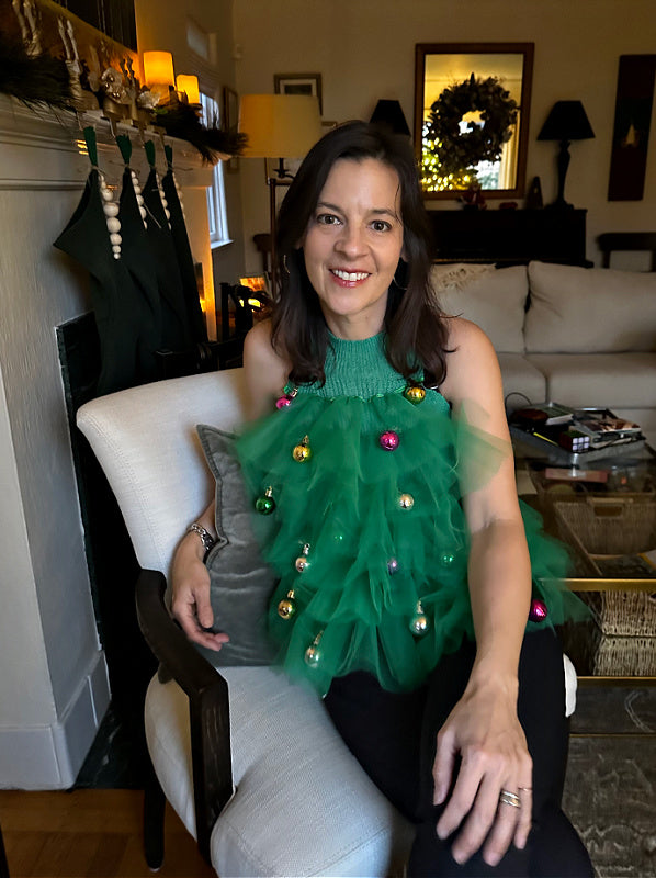 photo of woman seated in tree top ornament ugly sweater