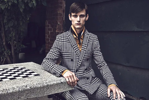 a male model wearing suit sitting on a bench