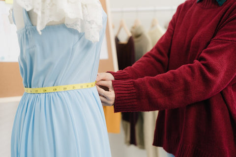 a lady taking measurements of a dress on dummy