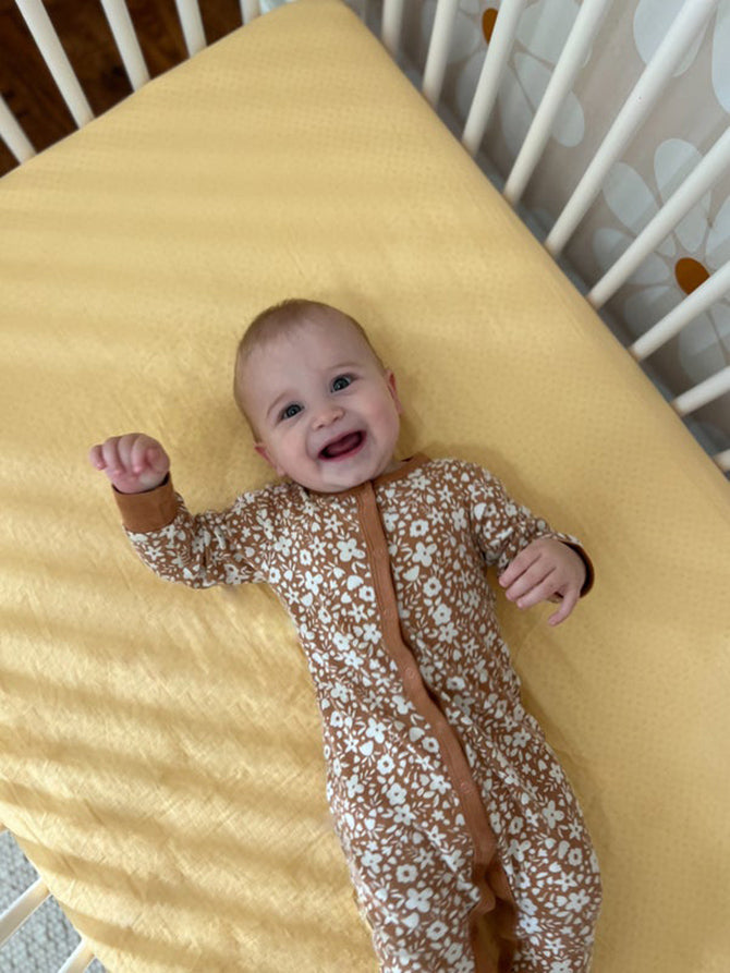 baby laying on back in crib