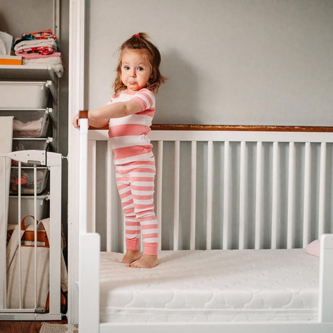 Pouty face girl standing in her 4-in-1-crib