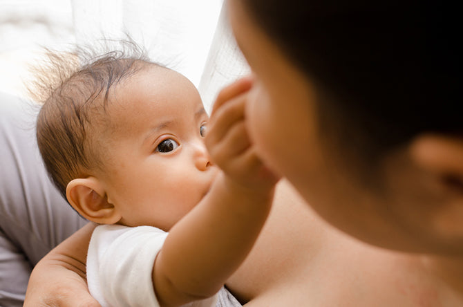 baby touching moms face while breastfeeding