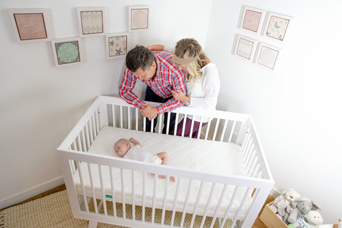 Parents looking over baby in crib