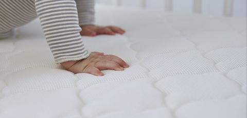 uplcose of baby's hands on bassinet mattress