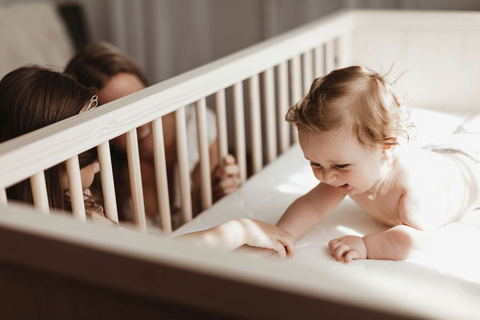 Family playing with baby in crib