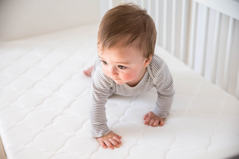 baby crawling on bassinet mattress