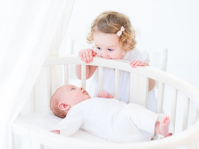 Sibling looking at newborn in a bassinet