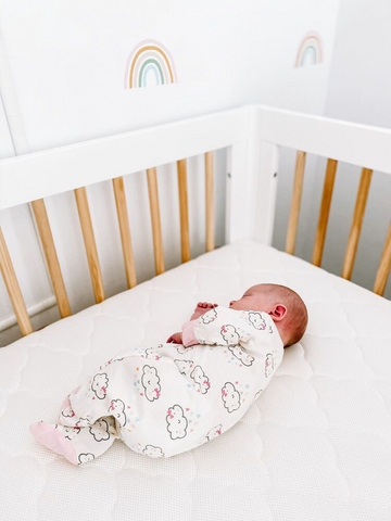 baby sleeping in crib with rainbows on walls