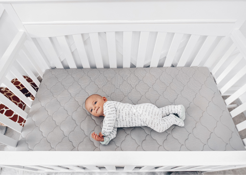 baby laying in crib with proper crib safety 