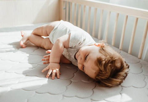Baby laying on side in crib with changing table