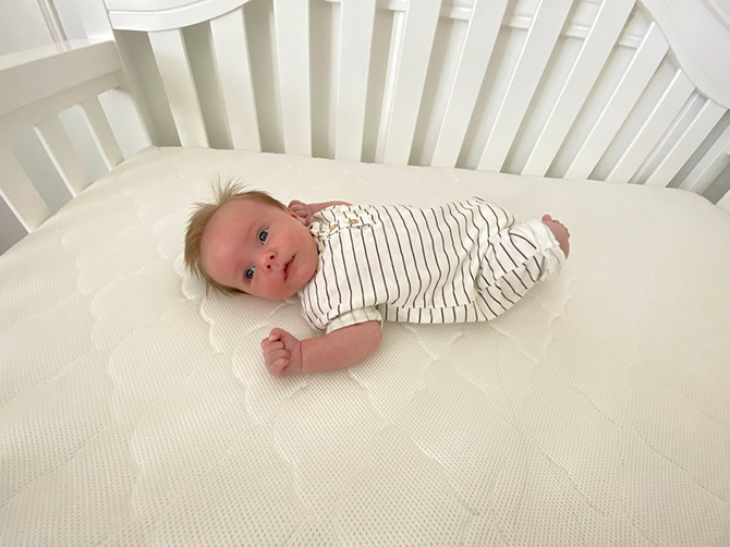 baby laying on crib mattress