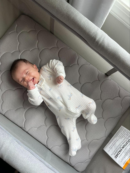baby laying on back in crib
