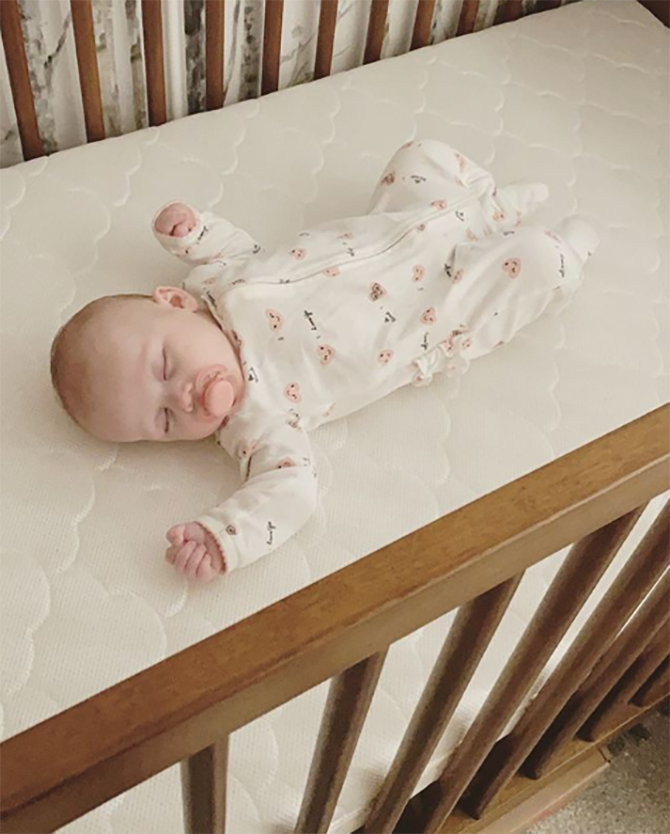 Baby laying in a crib in onesie