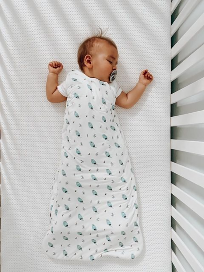 Baby wearing a swaddle blanket to show how to dress baby for sleep