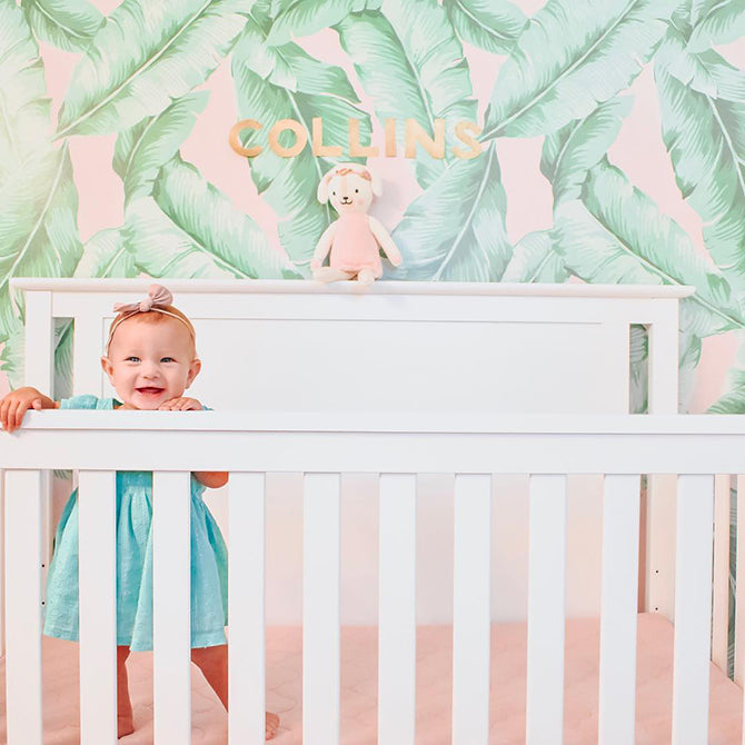 baby standing in crib in nursery