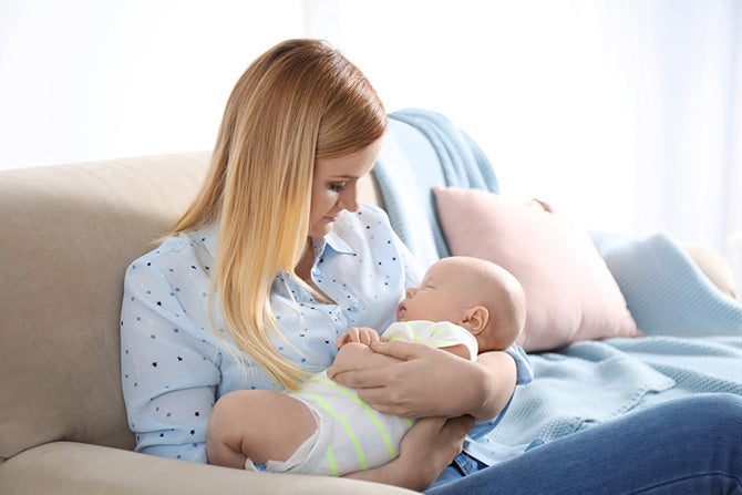 Mom holding baby while wondering how to get your baby to sleep without being held