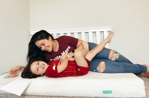 Mom tickling kid on mattress