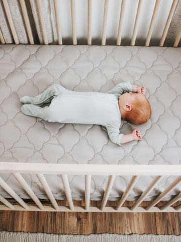 baby sleeping on bare crib mattress