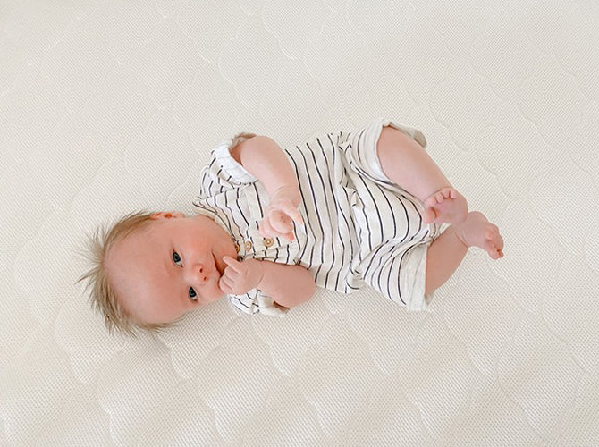 Baby laying on a newton crib mattress