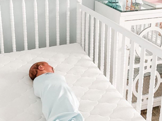 newborn sleeping on portable crib 