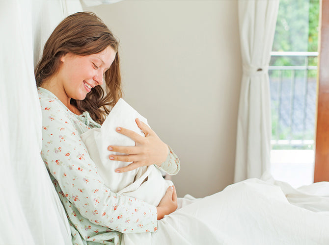 mom holding newborn thinking about postpartum essentials
